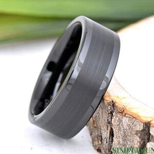 May include: A black tungsten carbide ring with a brushed finish and a beveled edge.