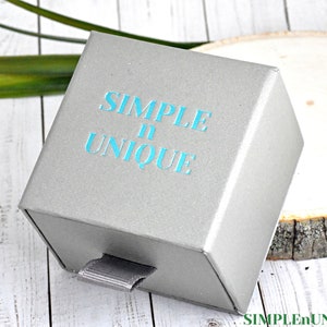 May include: A gray box with a drawer, the box has the text "SIMPLE n UNIQUE" printed on the top in teal blue lettering.