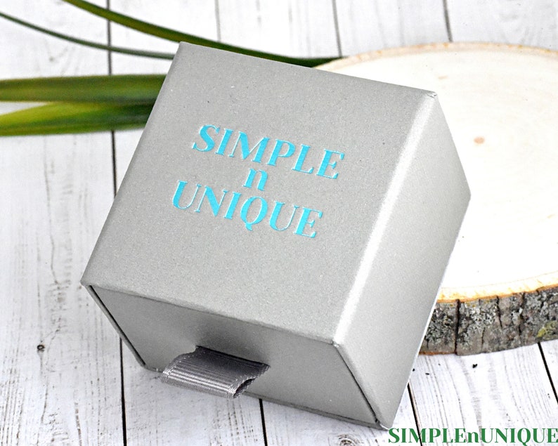 May include: A gray box with a drawer, the box has the text "SIMPLE n UNIQUE" printed on the top in teal blue lettering.