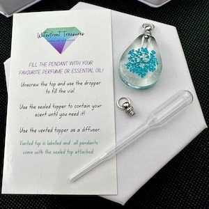 May include: A clear glass teardrop-shaped pendant with a blue flower pressed inside. The pendant comes with a small glass dropper and a metal stopper. The instructions on the card say "Fill the pendant with your favourite perfume or essential oil! Unscrew the top and use the dropper to fill the vial. Use the sealed topper to contain your scent until you need it! Use the vented topper as a diffuser. Vented top is labelled and all pendants come with the sealed top attached."