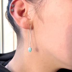 May include: A pair of silver chain earrings with a light blue leaf charm hanging from each chain.
