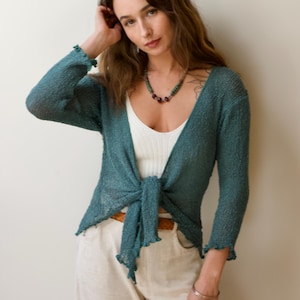 May include: A handmade wooden sign with the text "Welcome" in a whimsical font. The sign is painted white with a distressed finish, and features a decorative floral design in shades of pink and green. It measures approximately 12 inches wide.