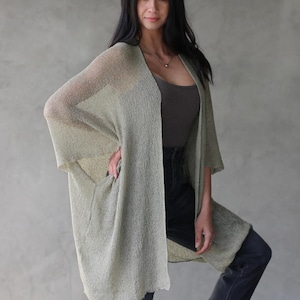 Può includere: Un cardigan verde chiaro aperto sul davanti con una vestibilità ampia e fluida. Il cardigan è realizzato in un tessuto leggero e trasparente e ha uno stile rilassato e casual.