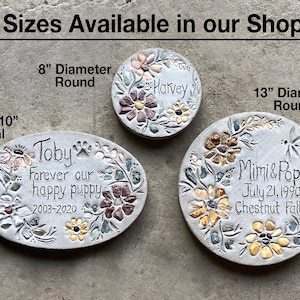 May include: Three decorative stone pet memorials in oval and round shapes. The oval memorial is 15" x 10" and the round memorials are 8" and 13" in diameter. Each stone features floral designs and personalized text.