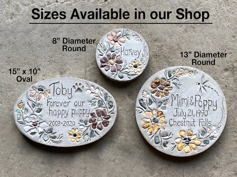 May include: Three decorative stone pet memorials in oval and round shapes. The oval memorial is 15" x 10" and the round memorials are 8" and 13" in diameter. Each stone features floral designs and personalized text.