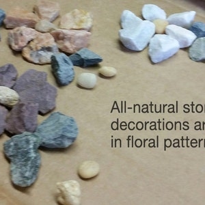 May include: Arrangement of natural stones in various colors, including gray, pink, and white, displayed in a floral pattern. The image includes the text "All-natural stone decorations arranged in floral pattern."