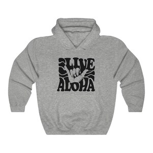May include: A gray hooded sweatshirt with a black graphic print of a hand making the shaka sign with the text "Live Aloha" in a retro font.