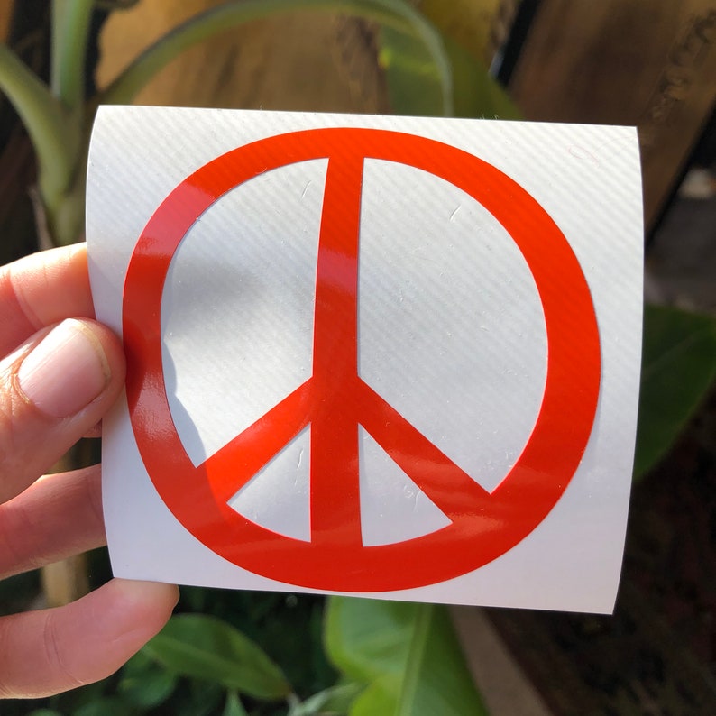 May include: A red peace sign sticker on a white background.
