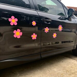 May include: A black car with pink and yellow flower decals on the side. The decals are in a retro style.