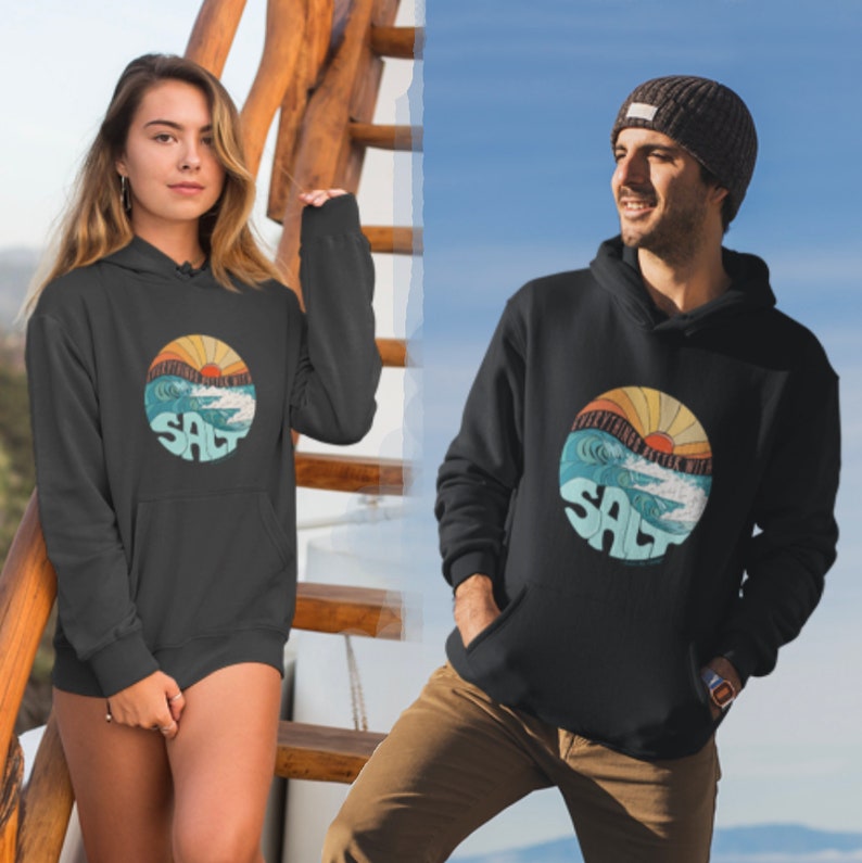 May include: Black hoodie with a graphic of a sunset over waves and the word "SALT" in a circle. The hoodie is shown on two models.
