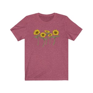 K&ouml;nnte beinhalten: Ein T-Shirt in Heide-Maroon mit einem Aufdruck von f&uuml;nf gelben Sonnenblumen mit gr&uuml;nen Stielen und Bl&auml;ttern.