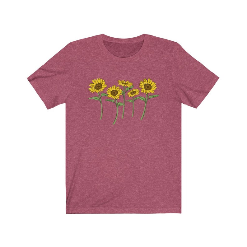 K&ouml;nnte beinhalten: Ein T-Shirt in Heide-Maroon mit einem Aufdruck von f&uuml;nf gelben Sonnenblumen mit gr&uuml;nen Stielen und Bl&auml;ttern.