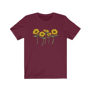 K&ouml;nnte beinhalten: Ein maroonfarbenes T-Shirt mit einem Aufdruck von f&uuml;nf gelben Sonnenblumen mit gr&uuml;nen Stielen und Bl&auml;ttern.