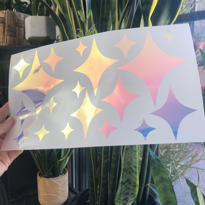 Puede incluir: Una hoja de pegatinas de vinilo iridiscente con 12 estrellas en forma de diamante en varios tonos de rosa, morado y dorado. Las pegatinas son perfectas para agregar un toque de brillo a cualquier proyecto.