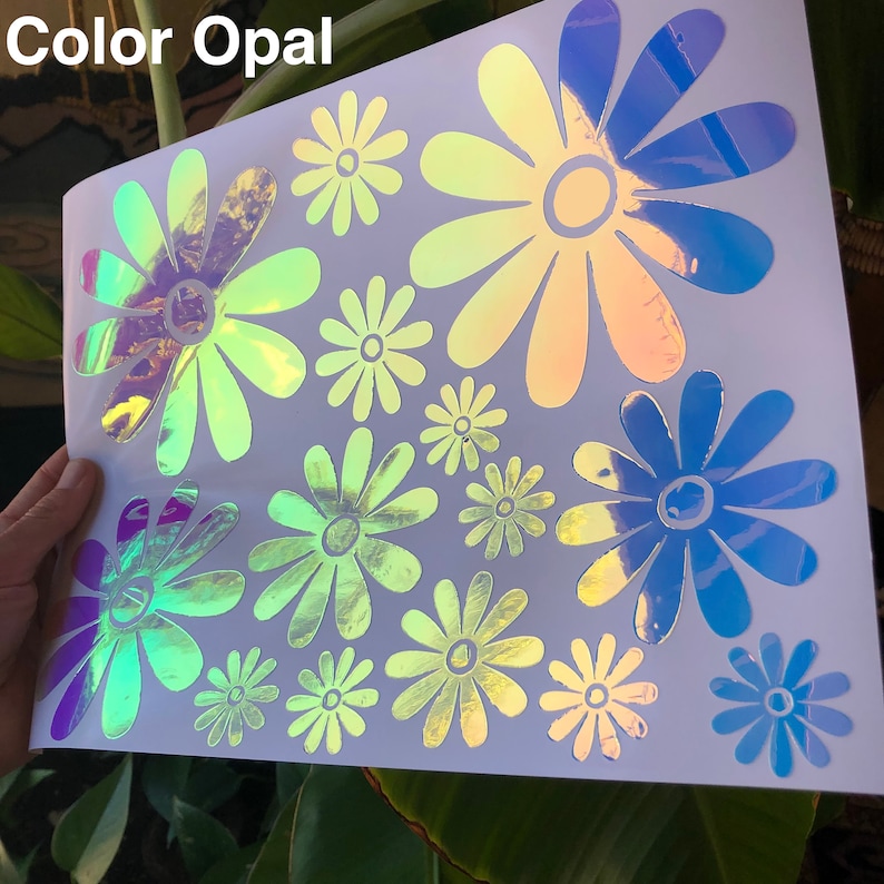 May include: A sheet of white paper with multiple iridescent daisy stickers in various sizes. The stickers are in shades of blue, green, and yellow.