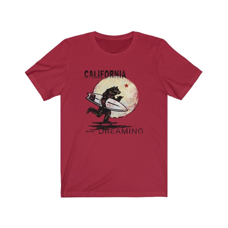 May include: Red t-shirt with a graphic of a bear surfing on a wave with a red star and the text "CALIFORNIA DREAMING" printed on it.