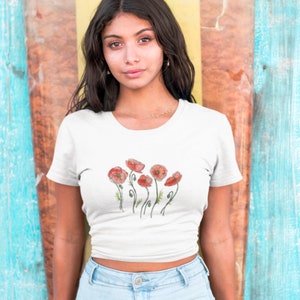 K&ouml;nnte beinhalten: Ein wei&szlig;es, bauchfreies T-Shirt mit einem Aufdruck von roten Mohnblumen auf der Vorderseite.