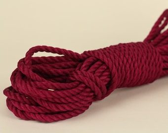 May include: A coil of thick, maroon-colored rope. The rope is made of natural fibers and has a rough texture.