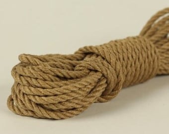 May include: A close-up of a thick, brown rope coiled into a neat bundle. The rope is made of natural fibres and has a rough texture.