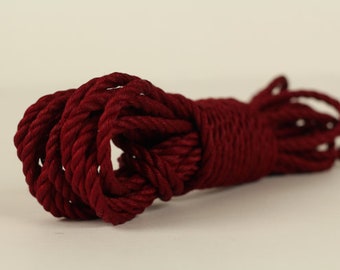 May include: A close-up of a tightly wound coil of thick, dark red rope.