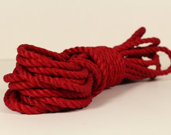 May include: A close-up of a red rope coiled into a circle. The rope is thick and has a rough texture.