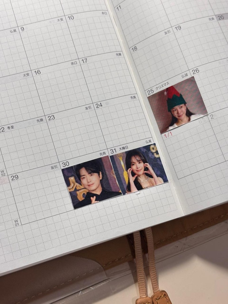 May include: A planner with a grid layout, featuring small photos of people and a Christmas-themed image. The planner's pages are open, displaying dates and Japanese characters. The photos are placed on specific dates.