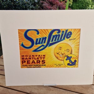May include: Vintage Sun Smile brand label for Mountain Bartlett Pears. The label features a smiling sun with a blue anchor logo and the text "Blue Anchor Exchange".