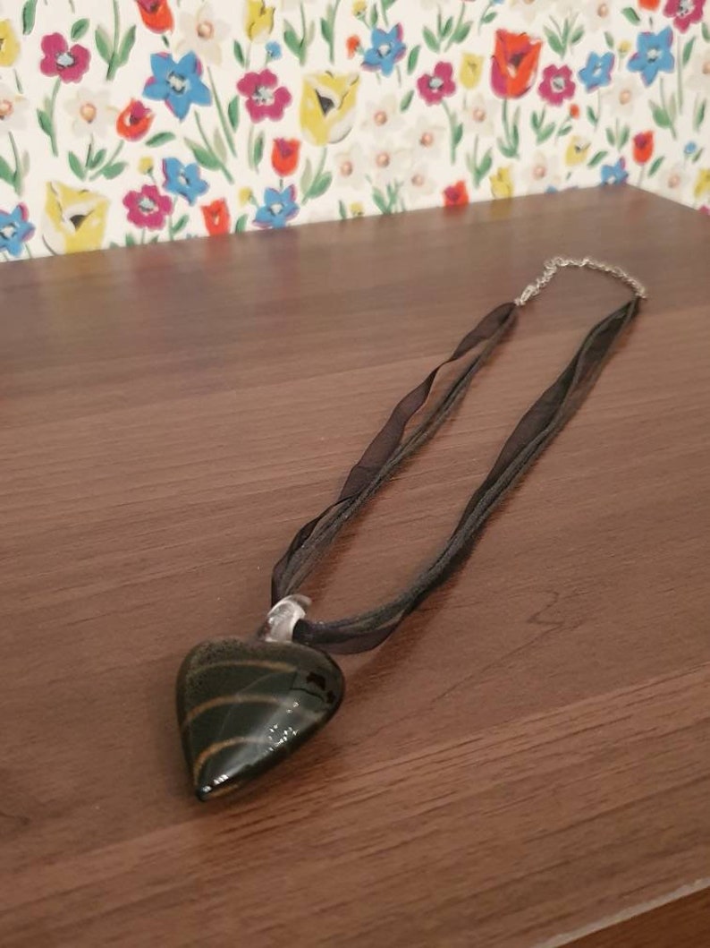 String necklace with black and gold stripe glass pendant in the shape of a heart.