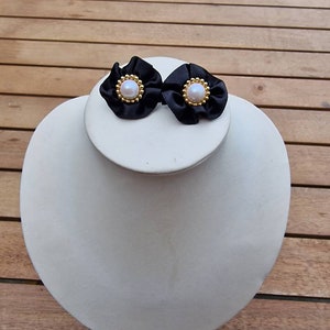 Vintage pierced earrings made from gold tone, plastic pearl centre and black material.