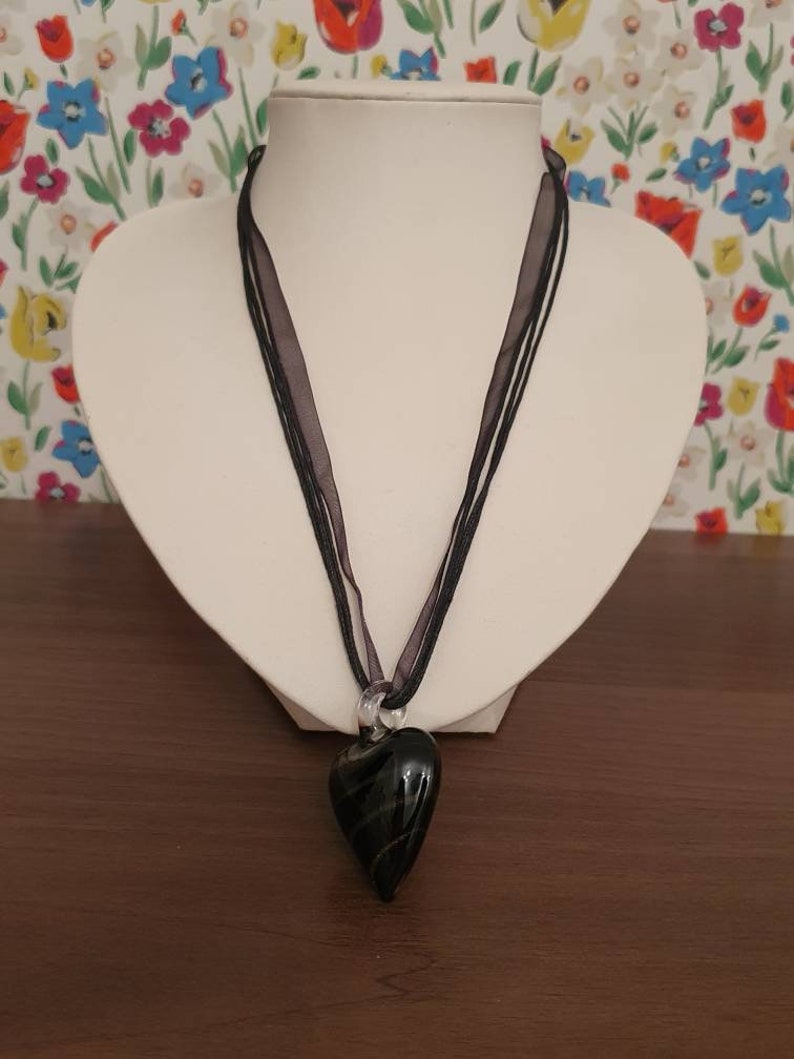 String necklace with black and gold stripe glass pendant in the shape of a heart.