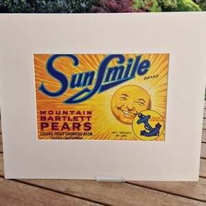 May include: Vintage Sun Smile brand label for Mountain Bartlett Pears. The label features a smiling sun face with a blue anchor and the text "Blue Anchor California Fruit Exchange".