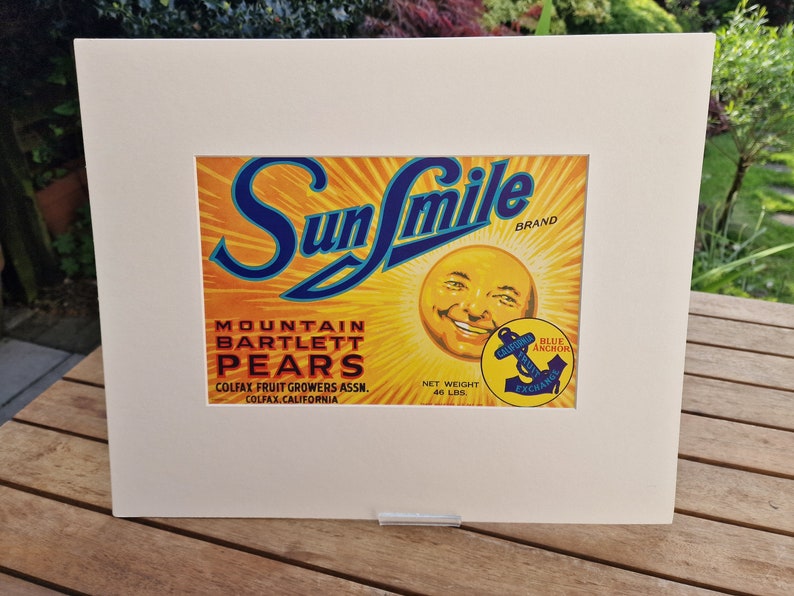 May include: Vintage Sun Smile brand label for Mountain Bartlett Pears. The label features a smiling sun face with a blue anchor and the text "Blue Anchor California Fruit Exchange".