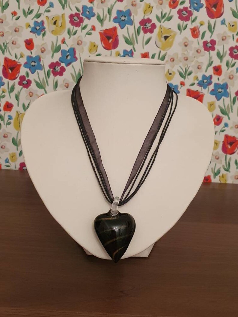 String necklace with black and gold stripe glass pendant in the shape of a heart.