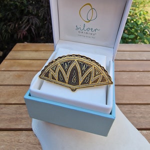 Vintage Damascene broche, waaiervorm met goudkleur en zwart design.
