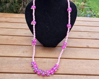 Vintage plastic necklace with pink beads and dark pink flowers.