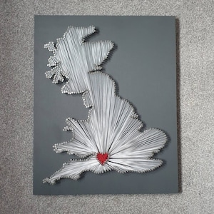May include: A grey wooden board with a white string art design of the United Kingdom. A red heart is in the centre of the design.