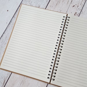 May include: An open spiral bound notebook with lined pages. The notebook has a brown paper cover.