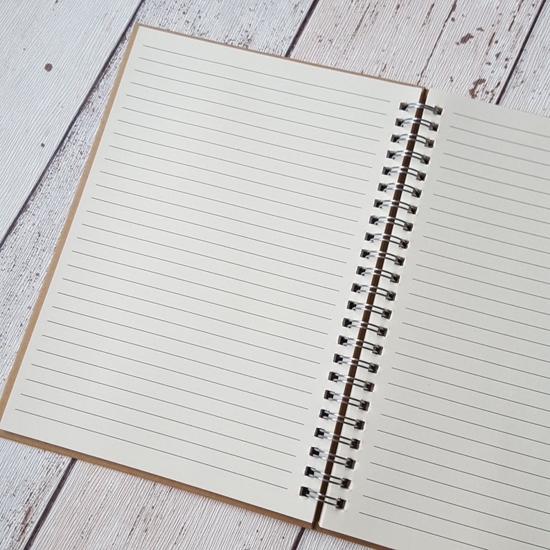 May include: An open spiral bound notebook with lined pages. The notebook has a brown paper cover.