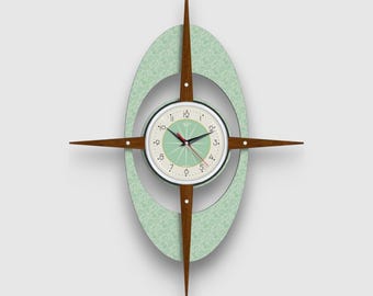 May include: A mid-century modern wall clock with a green oval frame and four wooden arms. The clock face is white with black numbers and hands.
