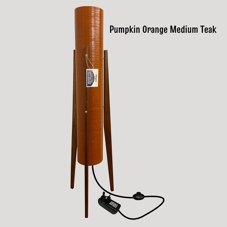 May include: A tall, orange floor lamp with a cylindrical shade and a teak wood tripod stand. The lamp has a black cord and a black plug.