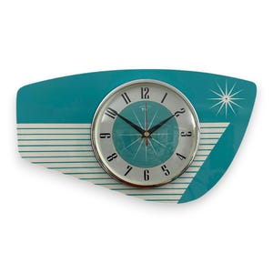 Könnte beinhalten: Eine türkisfarbene und weiße Wanduhr im Mid-Century-Modern-Stil mit einem Sternburst-Design. Das Zifferblatt der Uhr hat schwarze römische Ziffern als Stundenmarkierungen und schwarze Zeiger.