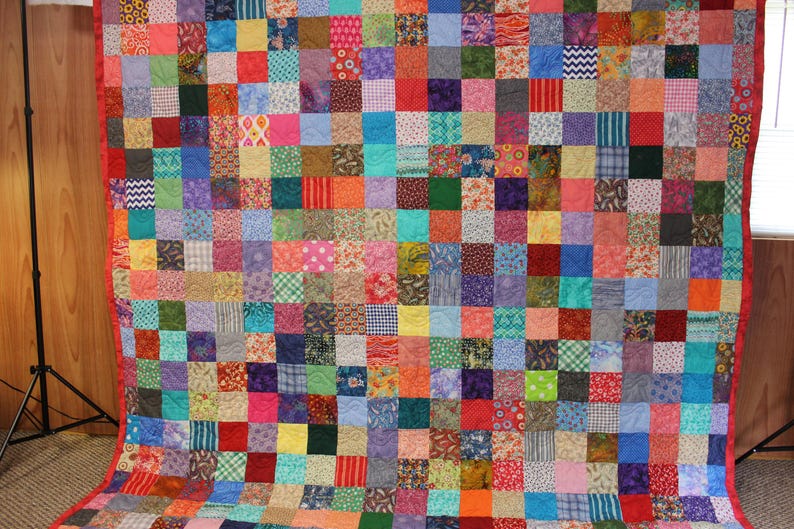 May include: A colorful patchwork quilt with a variety of fabrics and patterns. The quilt is made up of many small squares, each with a different design. The quilt is a vibrant mix of colors, including red, blue, green, yellow, and purple.
