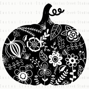 Op de afbeelding: Zwarte en witte pompoensilhouet met een wit bloemenpatroon. De pompoen heeft een steel en een gekrulde rank.