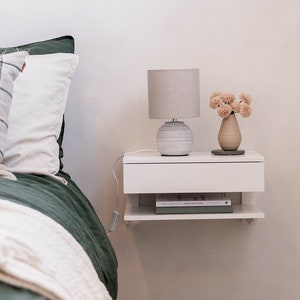 floating white bedside table. grey lamp and green bed covers
