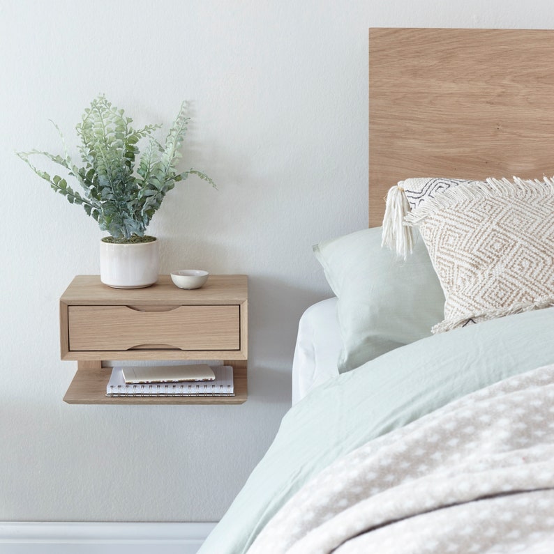 Floating oak bedside table next to oak bed