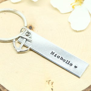 May include: Silver keychain with an anchor charm and a personalized bar that reads "Michelle" with a heart.