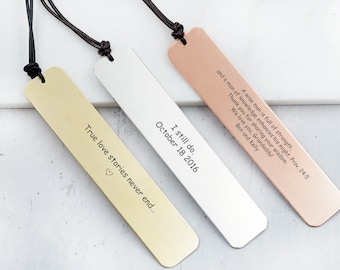 May include: Three gold, silver, and rose gold bookmarks with black leather straps. The bookmarks are engraved with different messages: "True love stories never end...", "I still do. October 18 2016", and "A wise man is full of strength, and a man of knowledge enhances his might. Prov. 24:5 Thank you for sharing your wisdom. We love you, Grandaddy! Ben and Kelly".