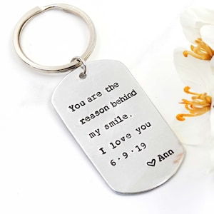 May include: Silver keychain with a tag that reads "You are the reason behind my smile. I love you 6.9.19 Ann" with a heart symbol before Ann.