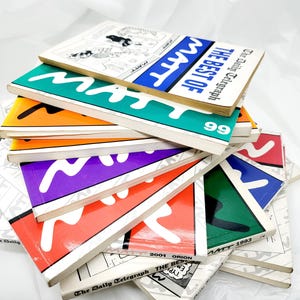 May include: A stack of colourful paperback books with the title "The Best of Matt" and the text "The Daily Telegraph" on the cover. The books are from different years, including 1993, 1999, and 2001.