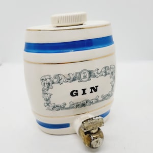 May include: White ceramic gin barrel with a blue stripe and gold trim. The barrel has a spout and a removable lid. The label reads "GIN".